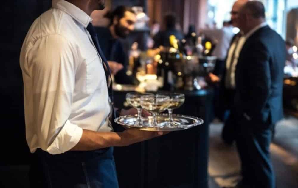 a waiter carrying some drinks in a bar