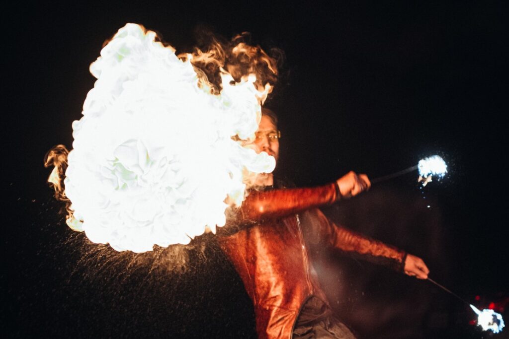 dazzling fire entertainer waving batons covered in fire