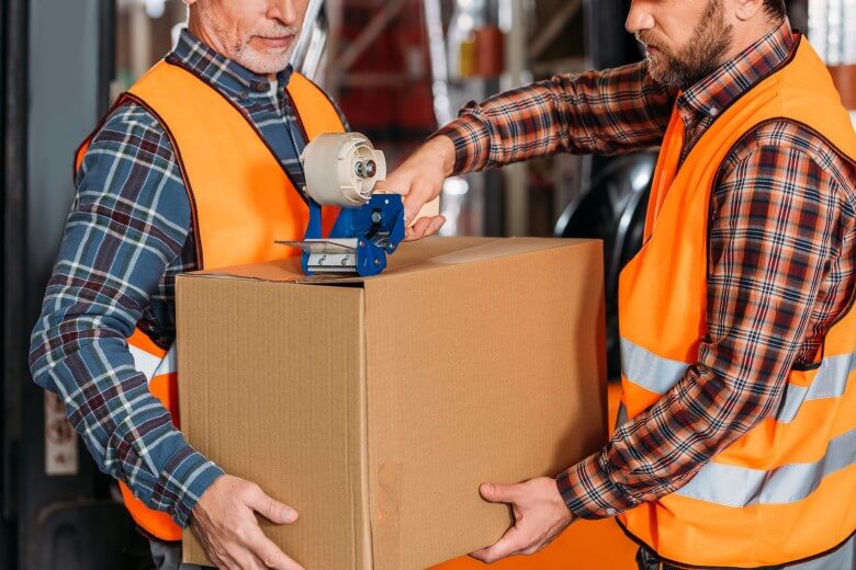 men carrying boxes in high vis jackets